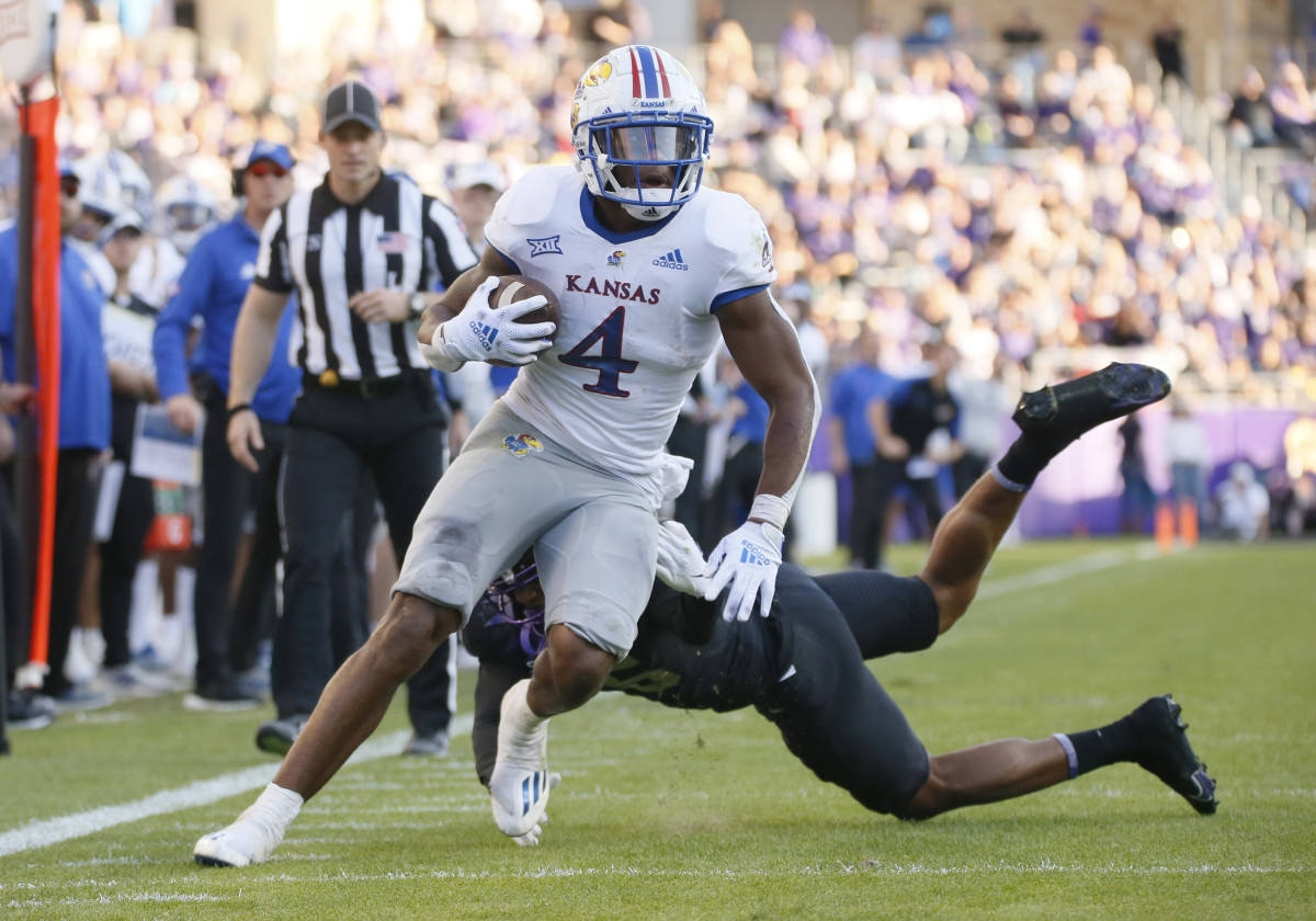 Nov 20, 2021; Fort Worth, Texas, USA; Kansas Jayhawks running back Devin Neal (4) turns the corner on TCU Horned Frogs linebacker Jamoi Hodge (6) during the first half at Amon G. Carter Stadium. Mandatory Credit: Raymond Carlin III-USA TODAY Sports